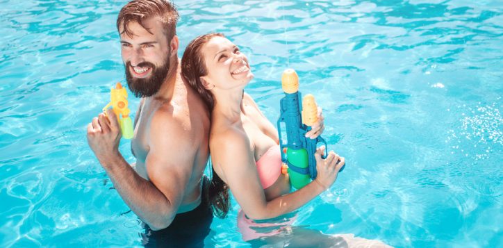 funny-couple-stands-swimming-pool-they-pose-smile-girl-looks-up-they-hold-water-guns-hands-they-are-ready-shoot-1-2